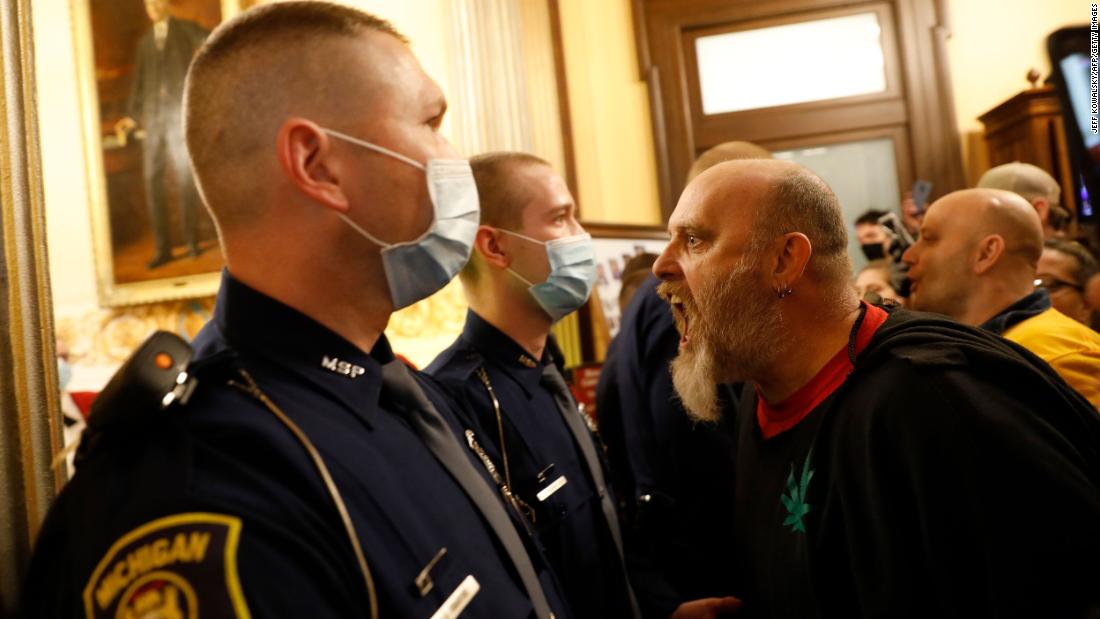 Michigan state police prevent protesters from entering the chamber of the Michigan House of Representatives on April 30. The protesters were unhappy with the state&#39;s stay-at-home order. Gov. Gretchen Whitmer recently extended the order through May 15, though restrictions were relaxed so some businesses could reopen.